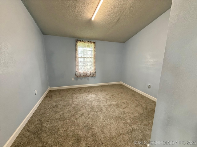 carpeted spare room with a textured ceiling and baseboards