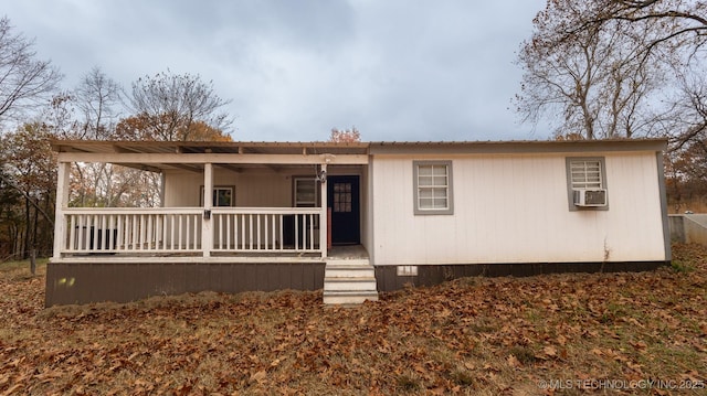 rear view of house with metal roof, cooling unit, and a porch