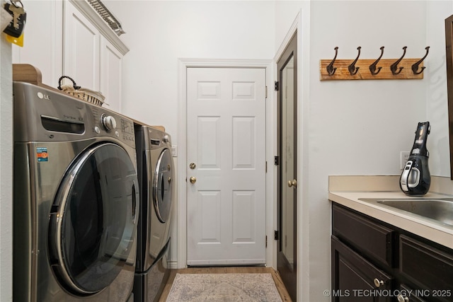 clothes washing area featuring separate washer and dryer, cabinet space, and light wood-type flooring