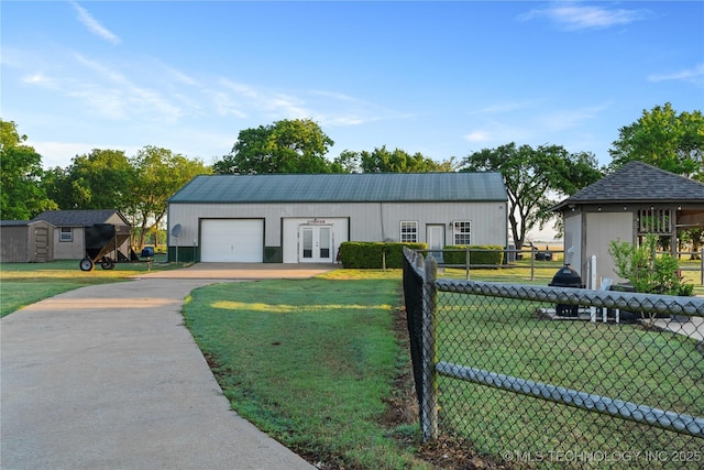 view of front of property featuring fence, a garage, driveway, french doors, and a front lawn