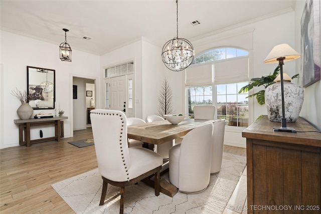 dining space featuring a chandelier, visible vents, ornamental molding, and light wood finished floors