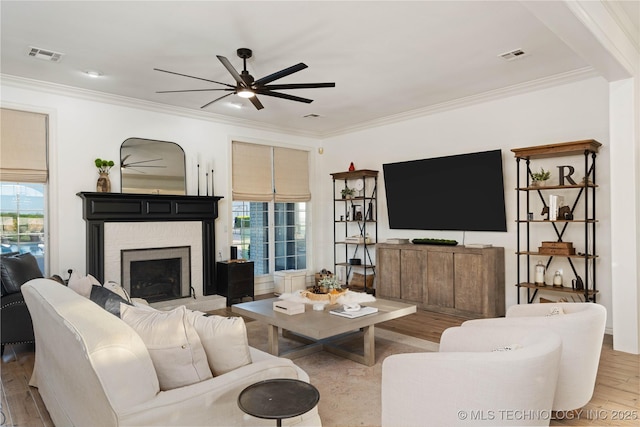 living room with ornamental molding, wood finished floors, ceiling fan, and visible vents