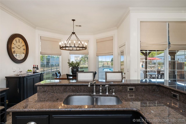 kitchen with dark stone counters, a notable chandelier, and a sink