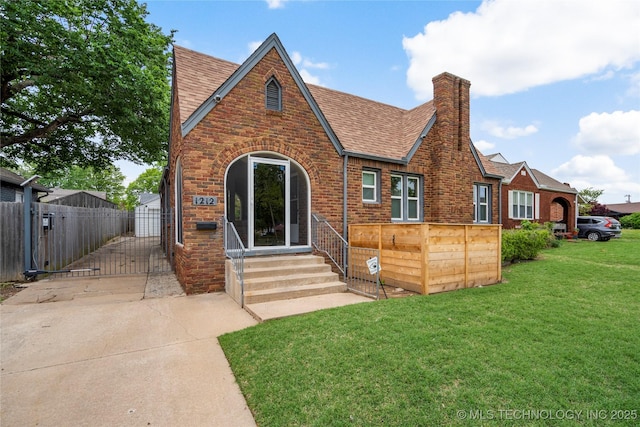 1212 S Knoxville Ave, Tulsa, OK 74112 - english style home featuring a gate, brick siding, fence, a shingled roof, and a front yard
