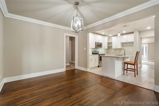 1212 S Knoxville Ave, Tulsa, OK 74112 - kitchen with a kitchen bar, a notable chandelier, backsplash, ornamental molding, and appliances with stainless steel finishes