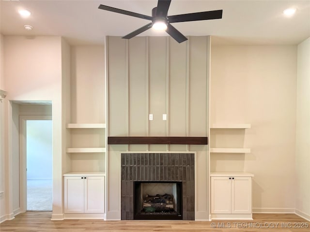 unfurnished living room featuring a tiled fireplace, recessed lighting, ceiling fan, and light wood-style flooring