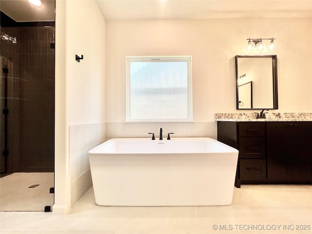 full bath featuring tile patterned floors, a stall shower, a freestanding bath, and vanity
