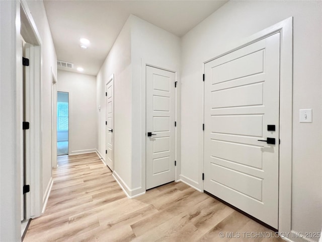 hall featuring light wood finished floors, recessed lighting, visible vents, and baseboards