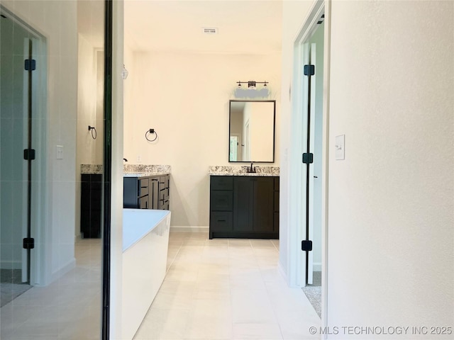 hallway with baseboards, visible vents, light tile patterned floors, and a sink