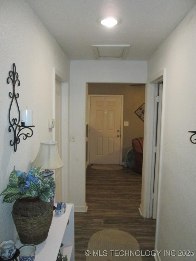 hallway with attic access and wood finished floors