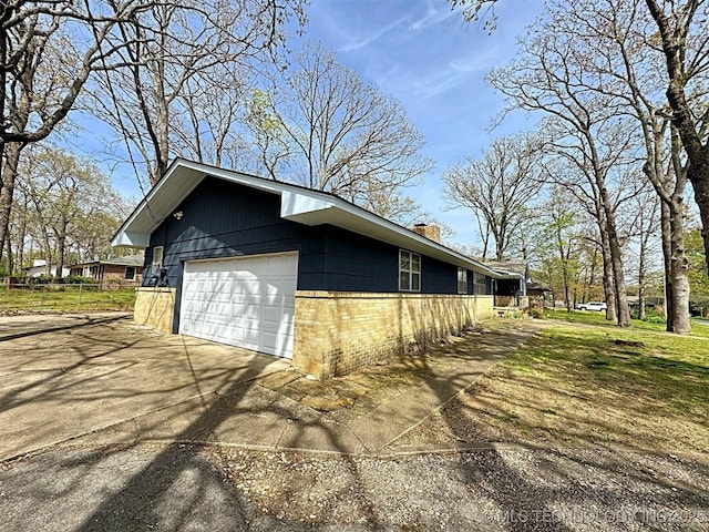 view of property exterior with a chimney, concrete driveway, and brick siding