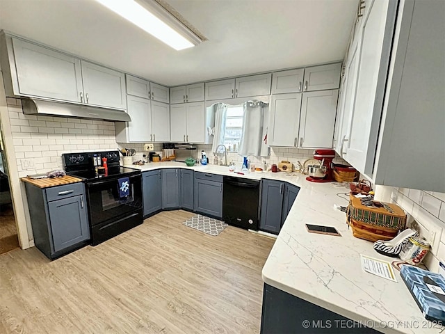 kitchen featuring under cabinet range hood, gray cabinetry, light wood finished floors, and black appliances