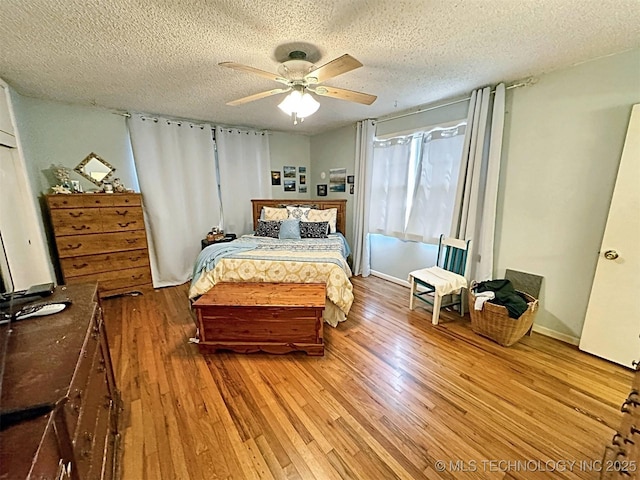 bedroom with a textured ceiling, ceiling fan, and wood finished floors