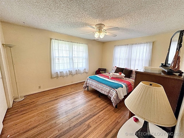 bedroom with baseboards, a textured ceiling, ceiling fan, and wood finished floors