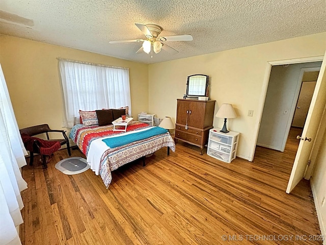 bedroom featuring a textured ceiling, a ceiling fan, and wood finished floors