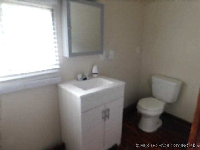 bathroom featuring toilet, wood finished floors, and vanity