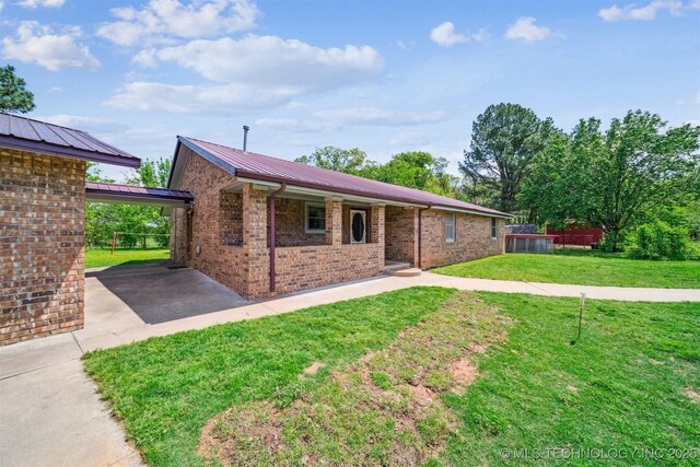 ranch-style house featuring concrete driveway, metal roof, brick siding, and a front lawn