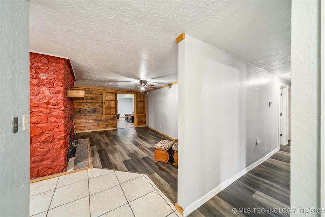 hallway with a textured ceiling, wood finished floors, and baseboards