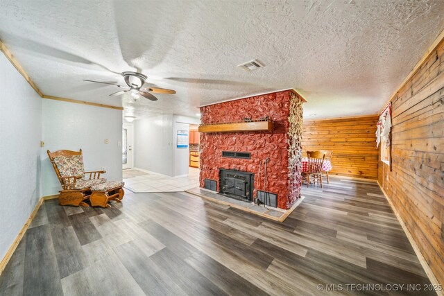 living room featuring visible vents, wood finished floors, a wood stove, and wooden walls