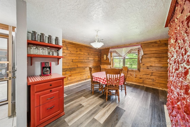 dining area with wood walls, wood finished floors, and a textured ceiling