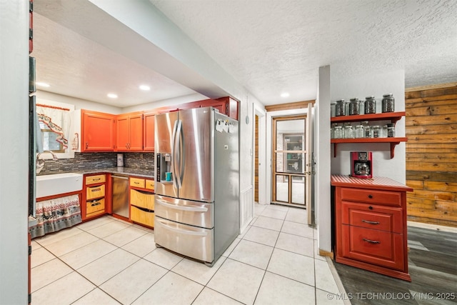 kitchen featuring light tile patterned floors, stainless steel appliances, backsplash, and a sink