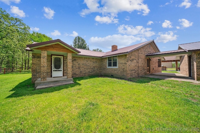 view of front of property featuring a chimney, brick siding, fence, metal roof, and a front lawn