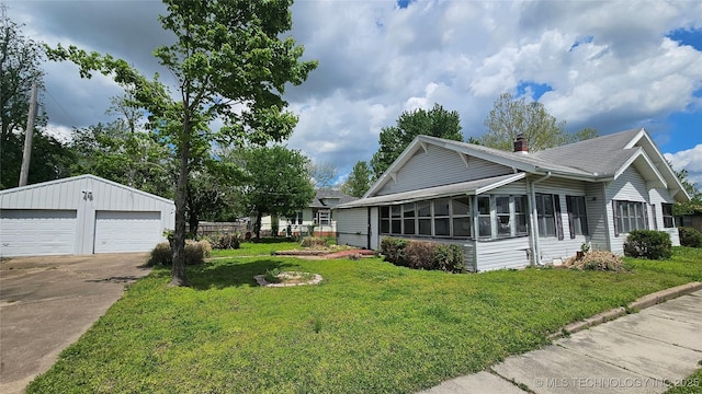 view of side of property with a chimney, an outdoor structure, roof with shingles, a detached garage, and a lawn