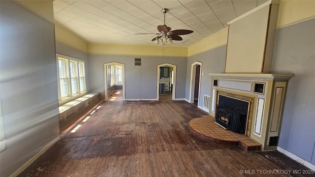 unfurnished living room with hardwood / wood-style flooring, crown molding, ceiling fan, visible vents, and baseboards