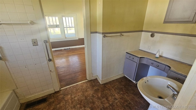 bathroom featuring tile walls, a sink, electric panel, a wainscoted wall, and visible vents