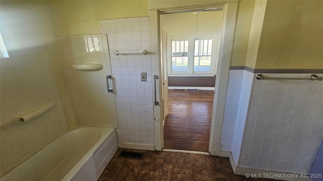 full bathroom featuring tile walls, visible vents, and wainscoting