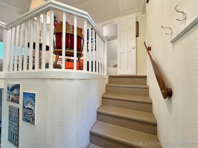 staircase with visible vents and a textured wall