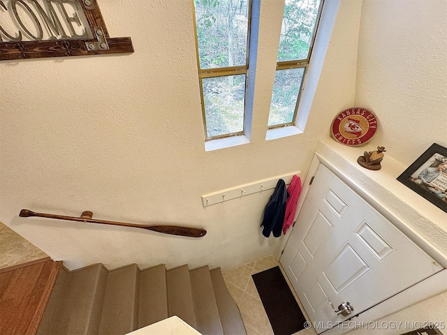 staircase with tile patterned floors and a textured wall