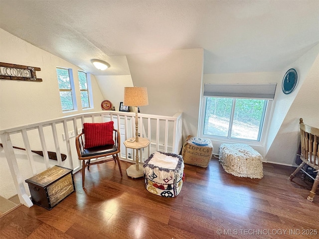 living area with an upstairs landing, vaulted ceiling, wood finished floors, and a textured ceiling