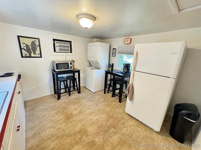 dining room with baseboards, stacked washer / dryer, a wall unit AC, and light floors