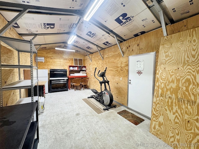 exercise room with a garage, wooden walls, and vaulted ceiling