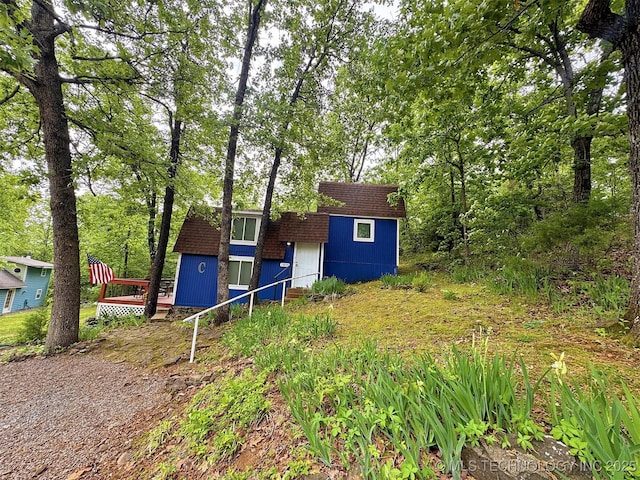 view of front of house with an outdoor structure, roof with shingles, and a storage shed