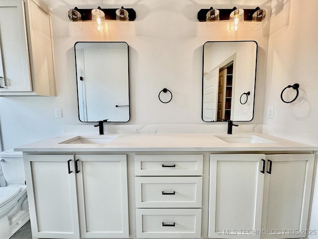 bathroom with double vanity, a sink, and toilet