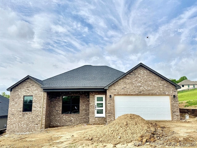 view of front of home featuring brick siding, a garage, and a shingled roof