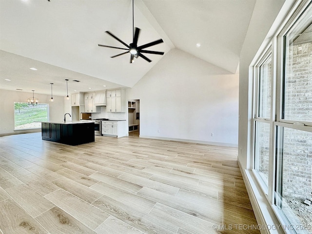 kitchen featuring open floor plan, white cabinets, ceiling fan with notable chandelier, and gas stove