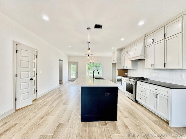 kitchen with gas stove, light wood-style flooring, custom range hood, and a sink