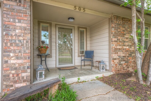 entrance to property with covered porch and brick siding