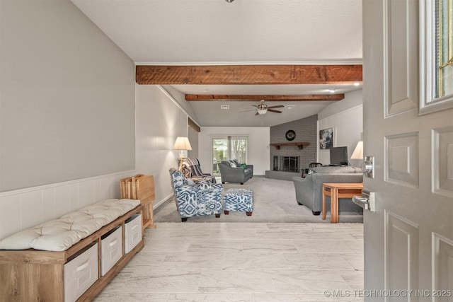 living room with vaulted ceiling with beams, a ceiling fan, a fireplace, and marble finish floor