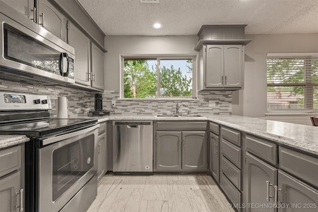 kitchen featuring a textured ceiling, a sink, appliances with stainless steel finishes, and gray cabinets