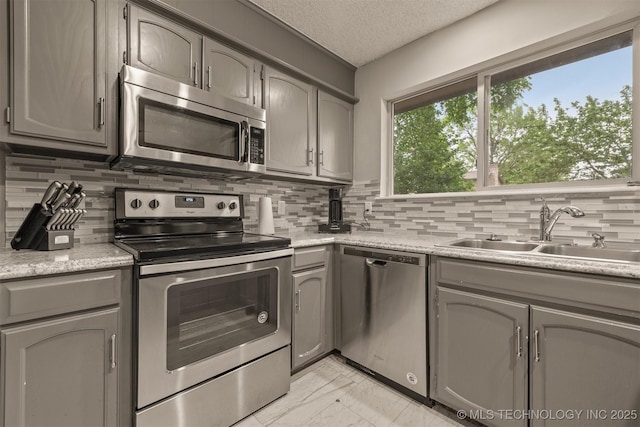 kitchen featuring appliances with stainless steel finishes, decorative backsplash, marble finish floor, and a sink