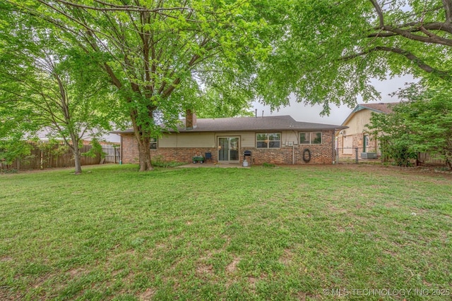 back of house featuring a chimney, a fenced backyard, and a yard