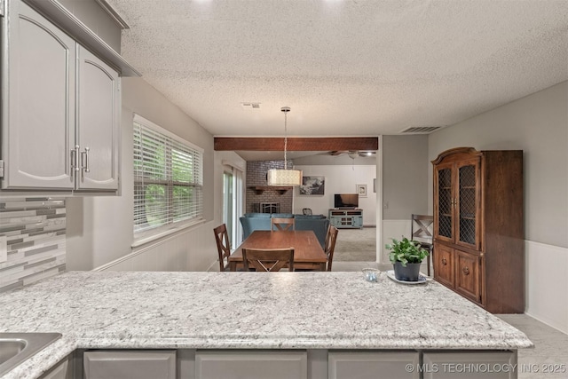 kitchen with a textured ceiling, ceiling fan, decorative backsplash, and visible vents