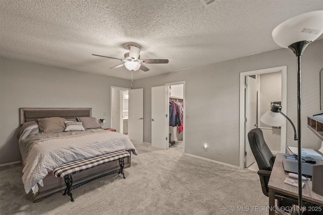 bedroom featuring baseboards, ensuite bath, a closet, light carpet, and a walk in closet