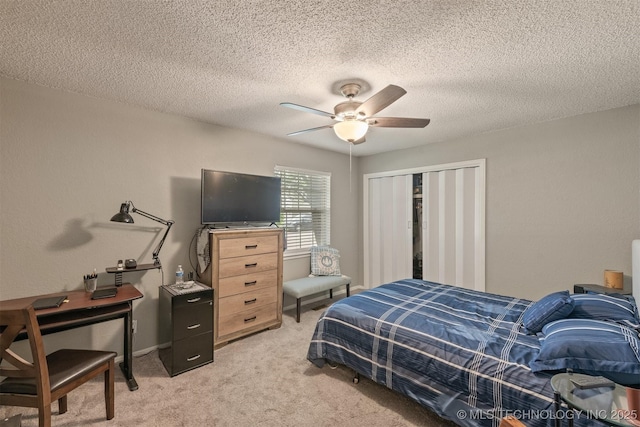 bedroom with a ceiling fan, light carpet, a textured ceiling, and a closet