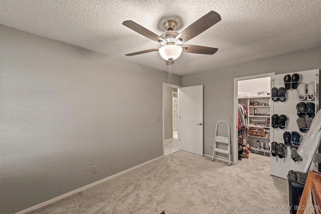 bedroom with a closet, ceiling fan, carpet flooring, a spacious closet, and a textured ceiling