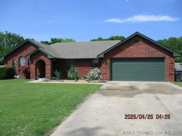 61 Cedar, Ardmore, OK 73401 - ranch-style house with a front yard, driveway, an attached garage, and brick siding